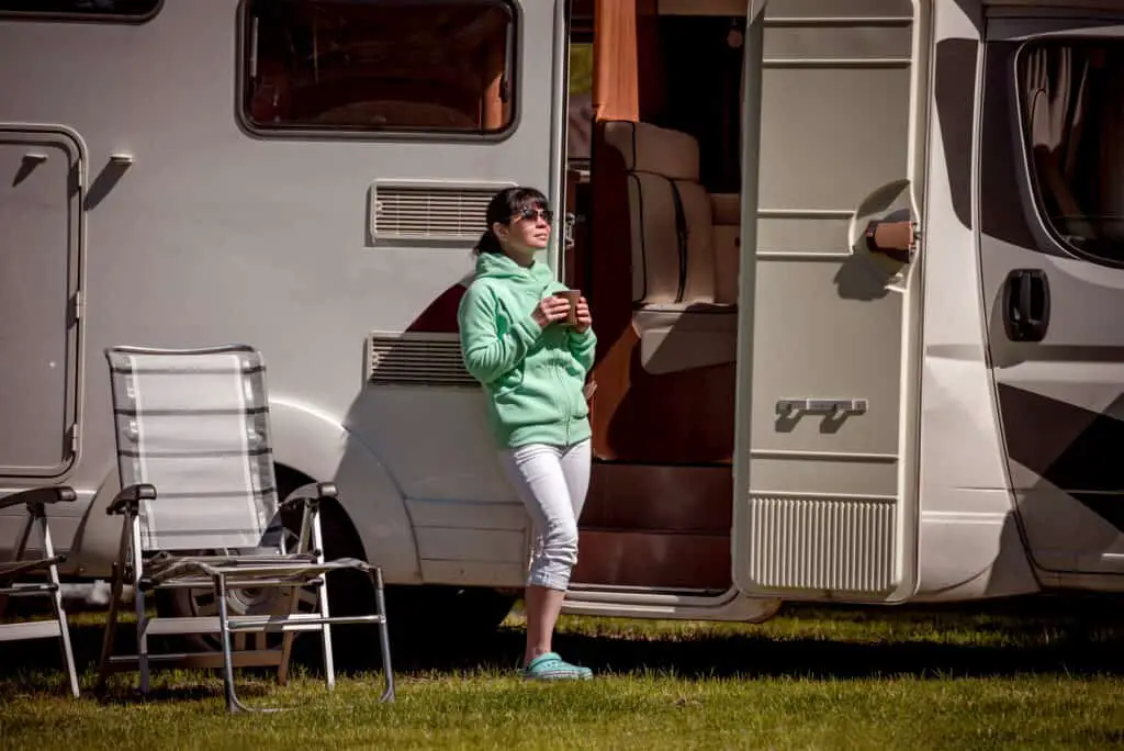 Woman enjoying gift of morning coffee in front of RV Camper