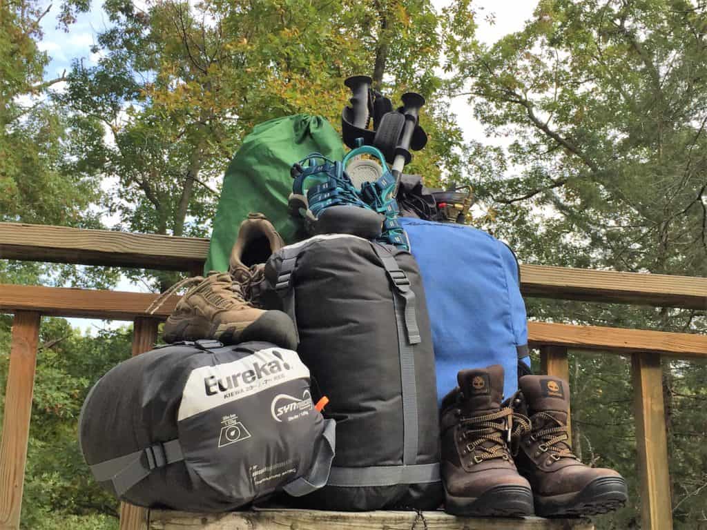 camping and hiking gear piled up on a deck