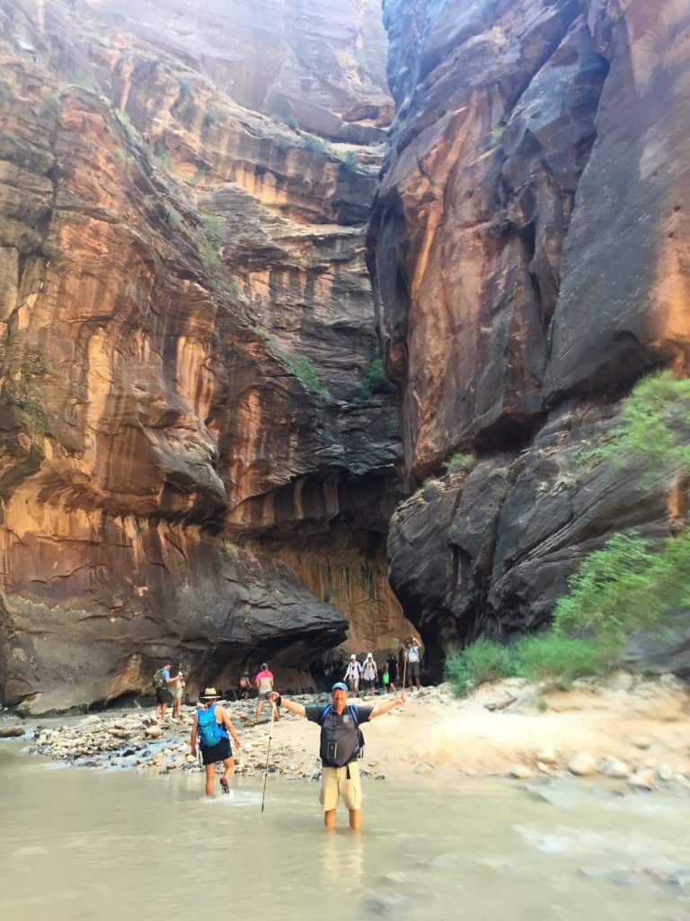 Hiking The Narrows Brad standing in water with tall canyon walls