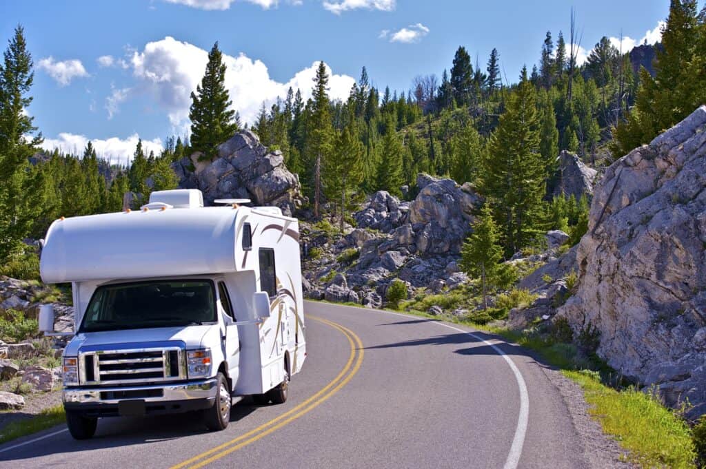 Camper on back of white truck driving down highway to reach campgrounds in Yellowstone National Park