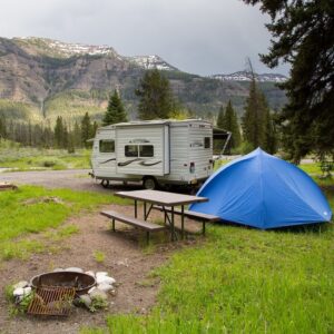 Blue tent in front of small white camper in Pebble Creek Campground in Yellowstone National Park