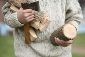 Man with firewood and camping hatchet