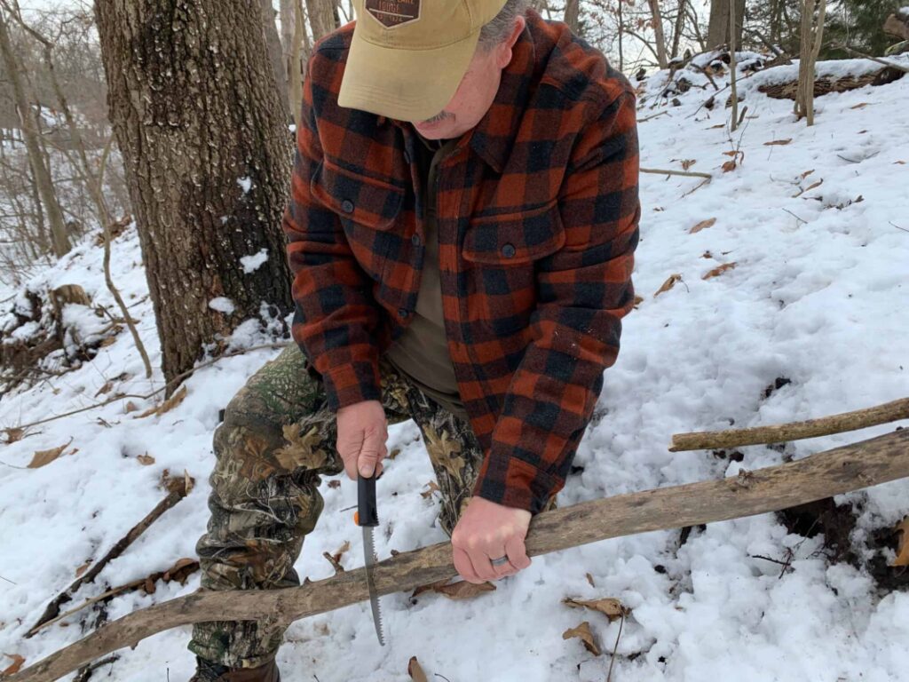 Brad cutting tree branch with folding camping saw