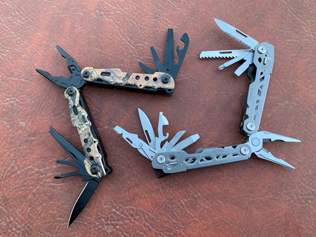 2 multi tools opened exposing all their tools laying on a leather bench