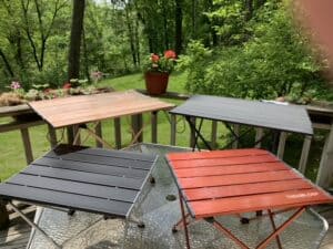 Four styles of folding side tables for camping sitting on a table