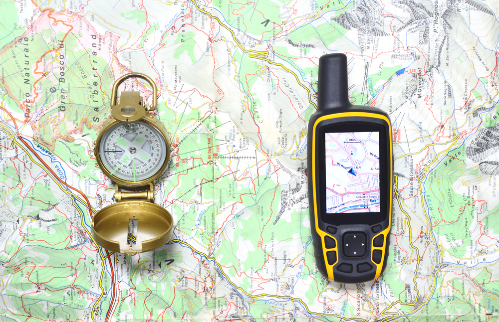 Map with compass and GPS unit demonstrating what to pack for a day hike