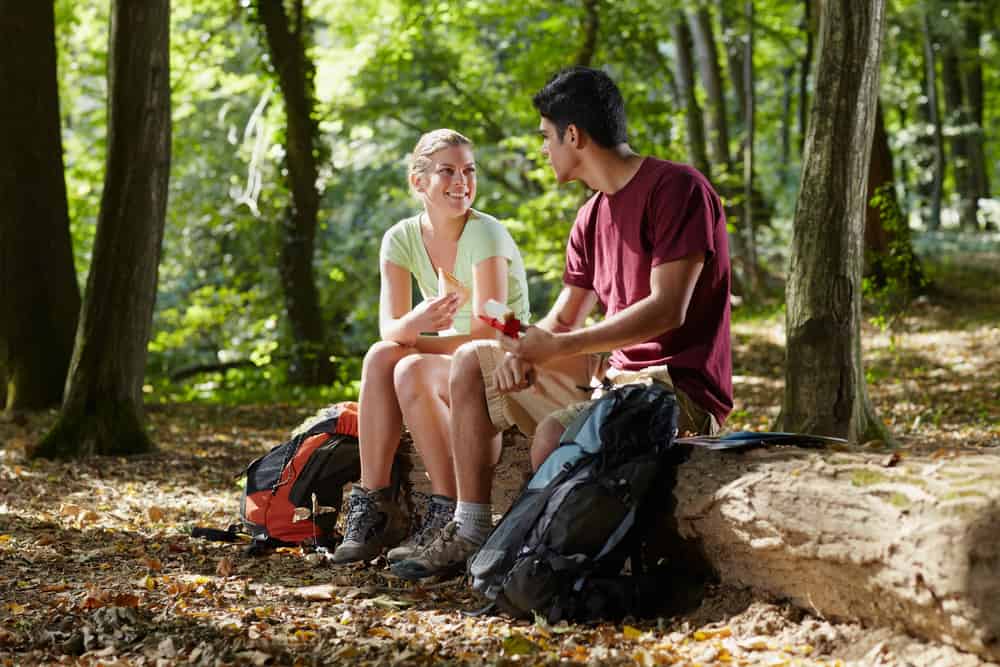 Couple sitting on log taking a break from hiking in hot weather