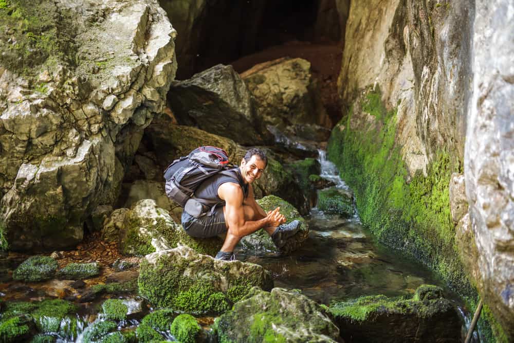 man hiking in hot weather along creek