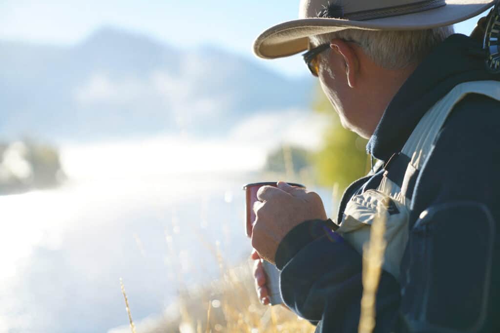 Fisherman enjoying a gift of morning coffee as he looks over the water.