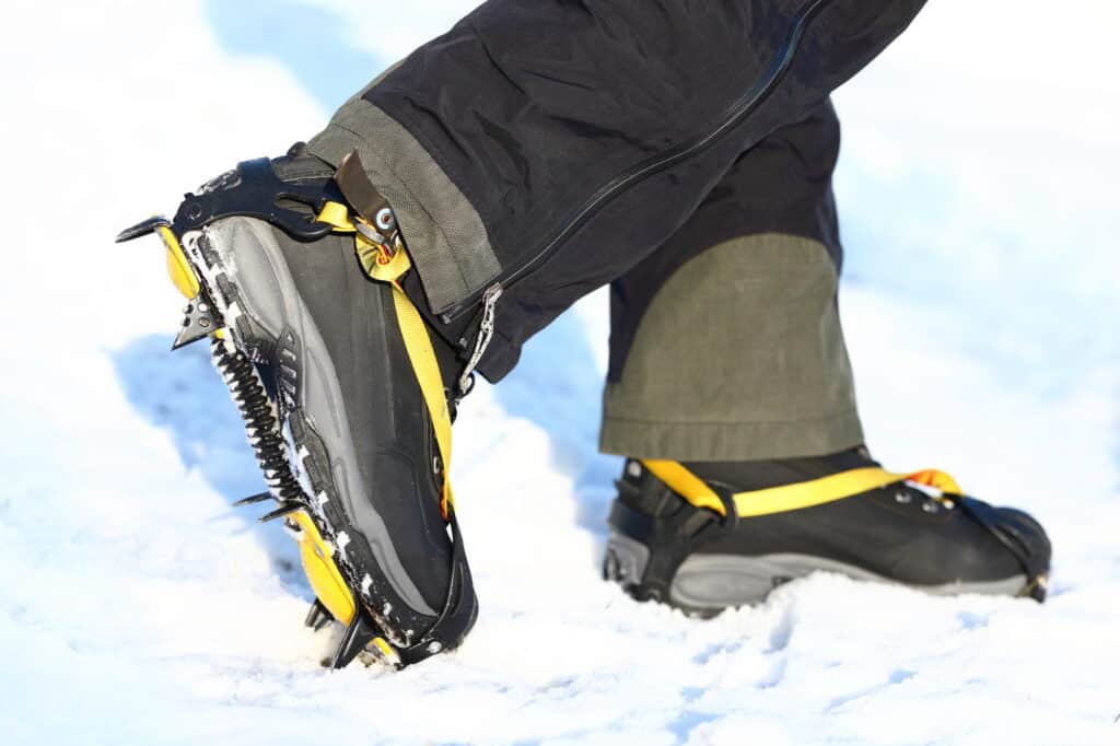 Trail Crampons and shoes walking on ice and snow during outdoor winter trekking. Close up.