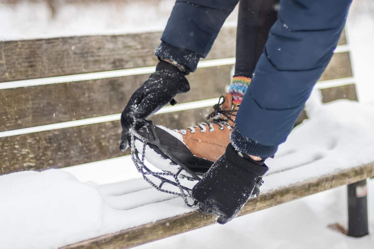 Woman putting traction device over boots in the snow