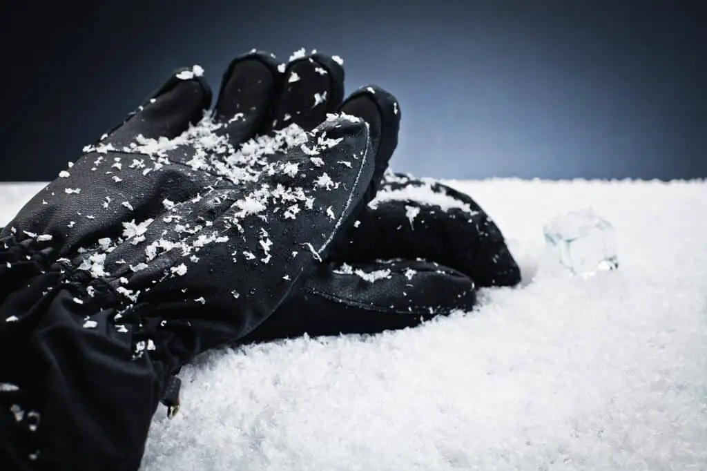 Black winter hiking gloves laying in snow