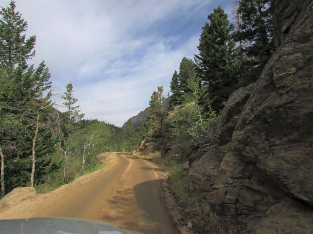 Dirt road lined with trees and a hairpin curve in the distance, a great way to start your trip when you only have 1 day in Rocky Mountain National Park