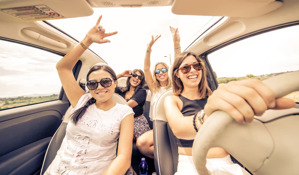 four girls in convertible laughing as they play travel games for adults