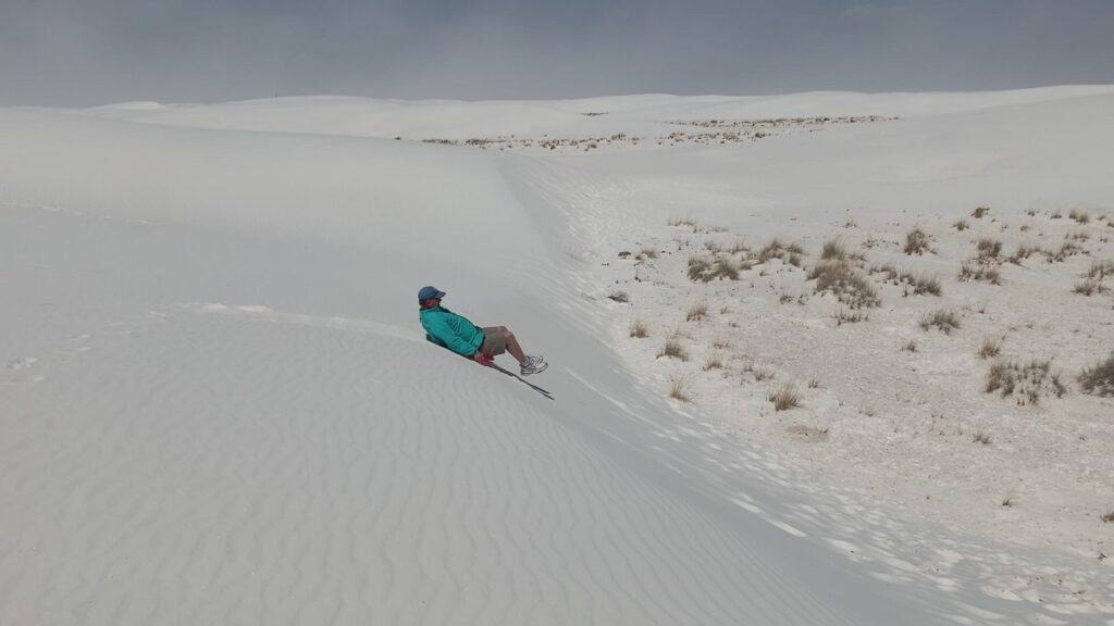 Brad sledding down sand dune in white sands national park