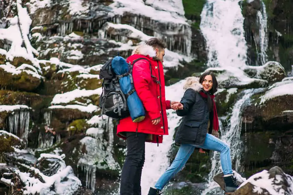 couple in denim jeans hiking in snow