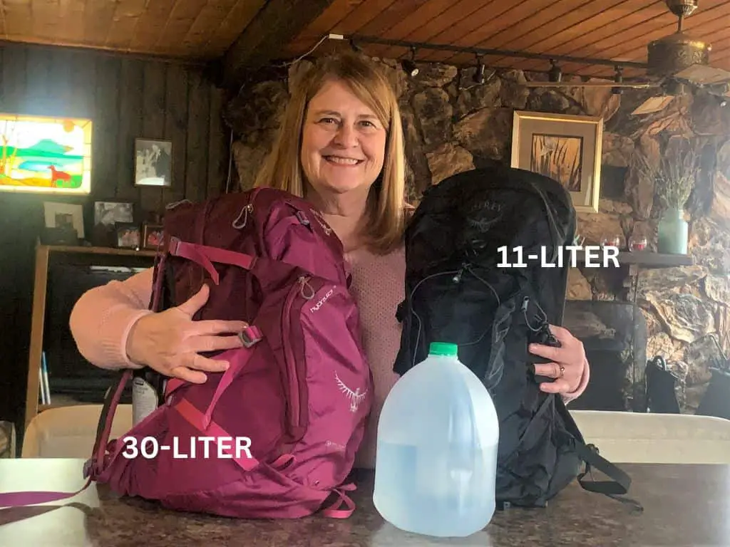woman holding 2 daypacks, one labeled as 30 liter, the other as 11 liter. Shows difference in size to help reader choose the best women's daypack.