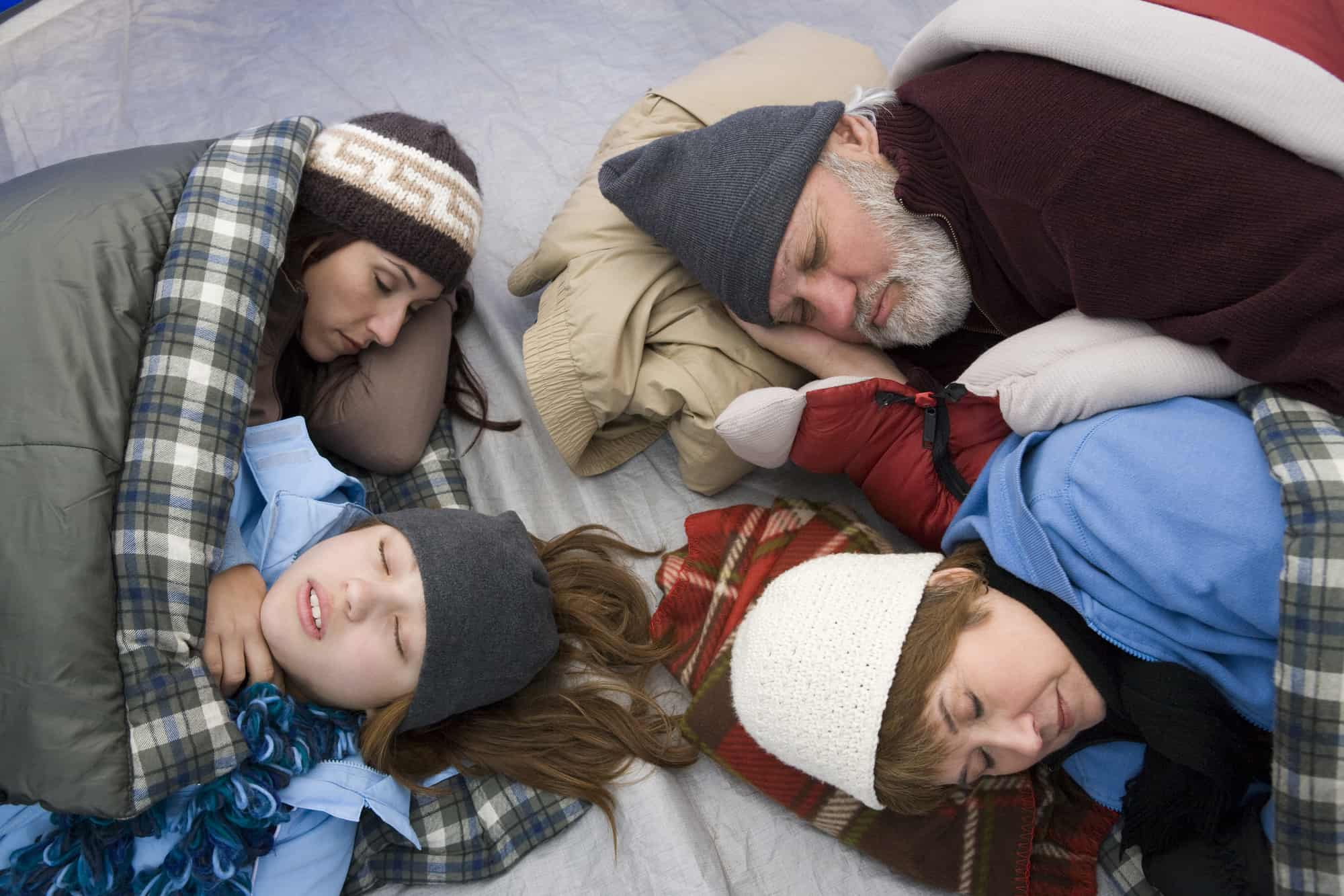 Family winter camping, all snuggled close together in tent