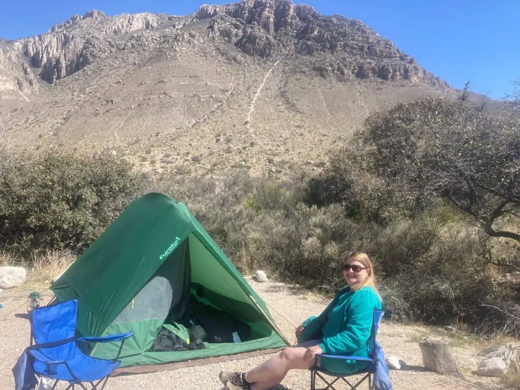 Woman sitting in front of green tent with Guadalupe Mountains in background