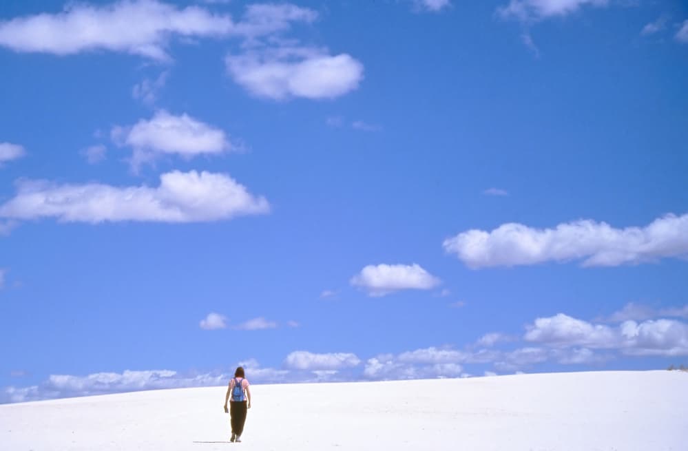 woman hiking accross the white sand