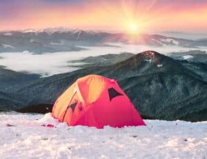 Orange Tent on snowy mountain as example of how to stay warm in a tent