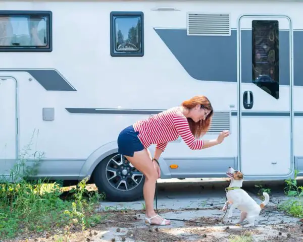 woman in front of RV giving treat to puppy