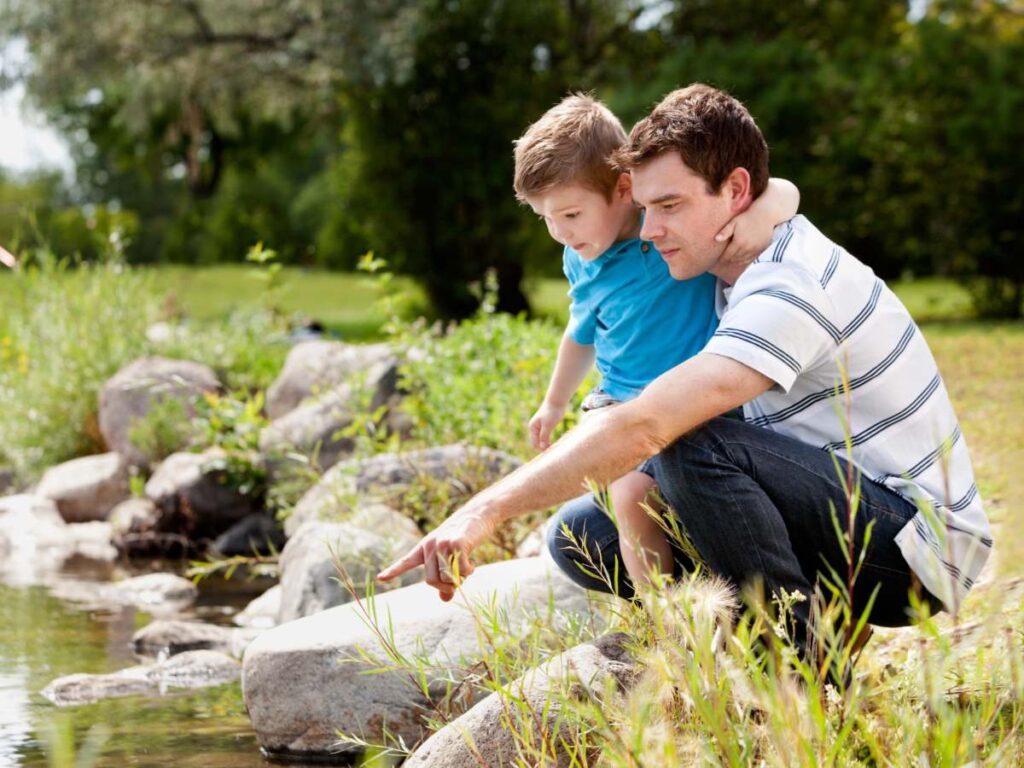 Dad and son looking at creek and pointing to something