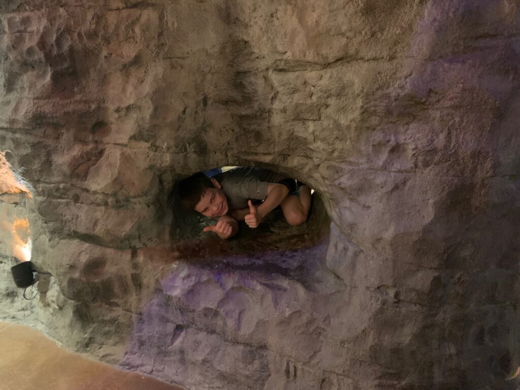 Boy in cave tunnel in the Mammoth Cave Museum, demonstrates size of some connecting tunnels between caves.