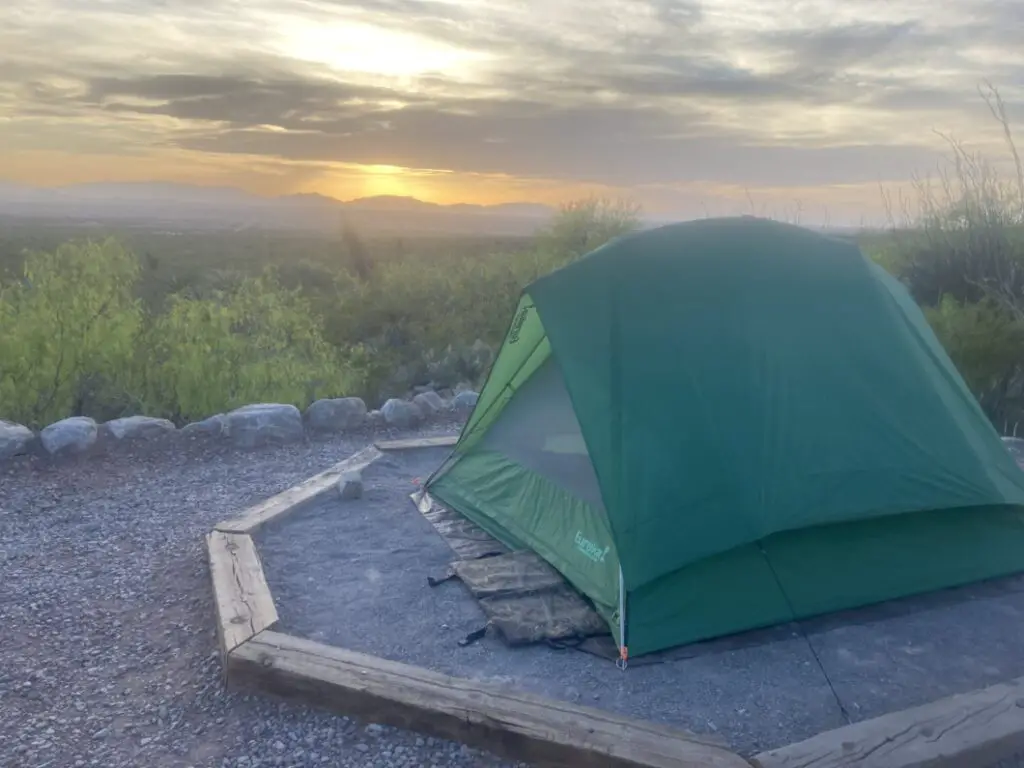 Green tent on tent pad with desert sunset in background