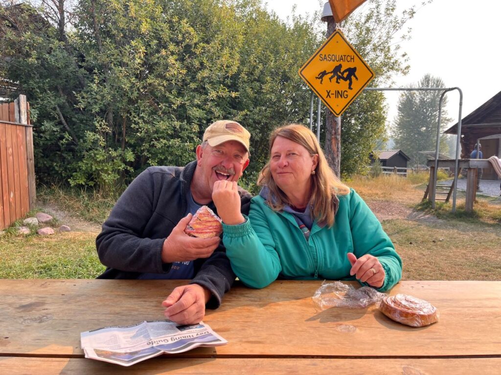 2 people eating pastries at a picnic table