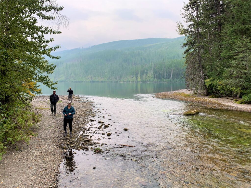 3 hikers walking along rocky shore of kintla creek in Glacier national park