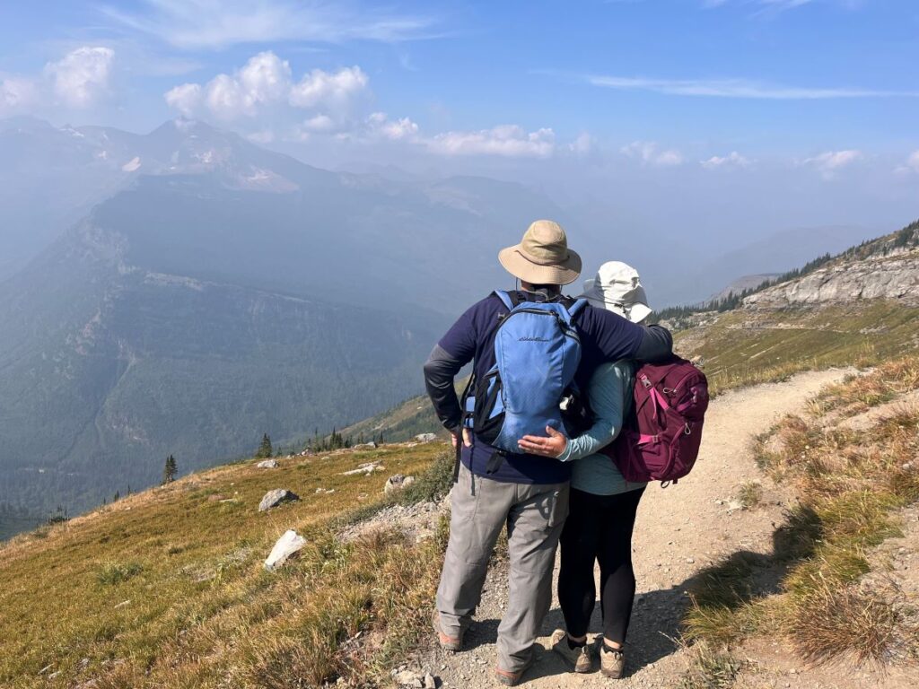 man and woman with back to camera looking over the mountains from the highline trail