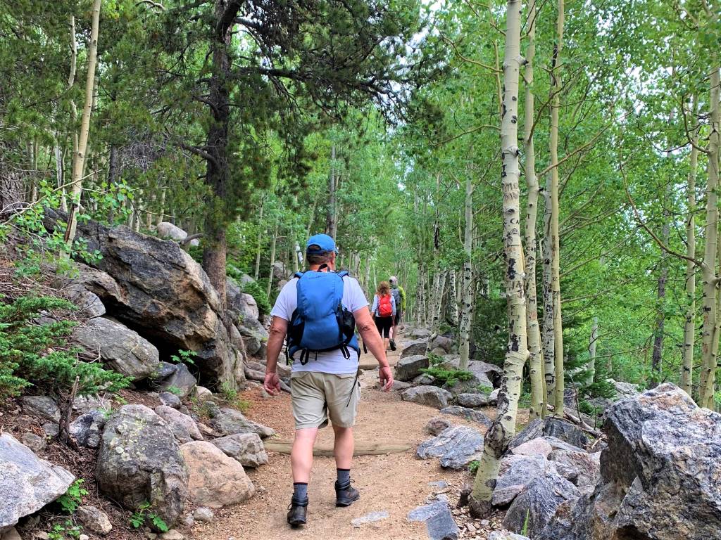Man hiking on dirt path with large rocks lining the trail. Bierstadt Lake Trail in rocky Mountain National Park