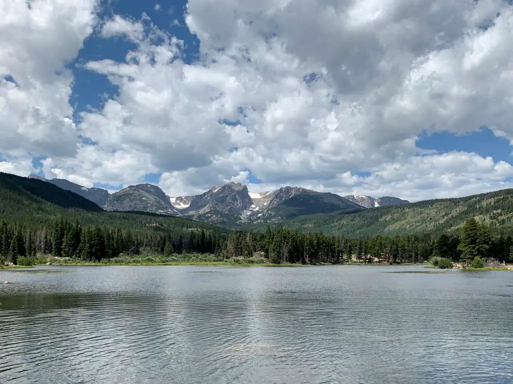 Calm view of Sprague lake with mountains in distance.