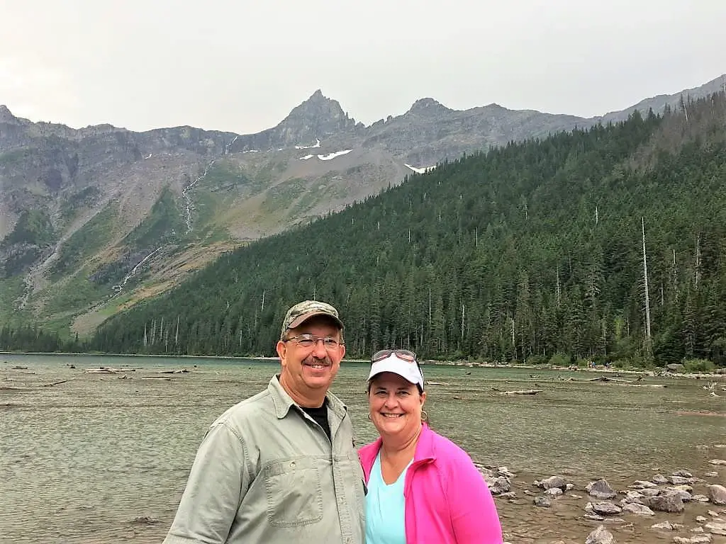 Brad and Ladona standing in front of Avalanche Lake, mountains with waterfalls in the background