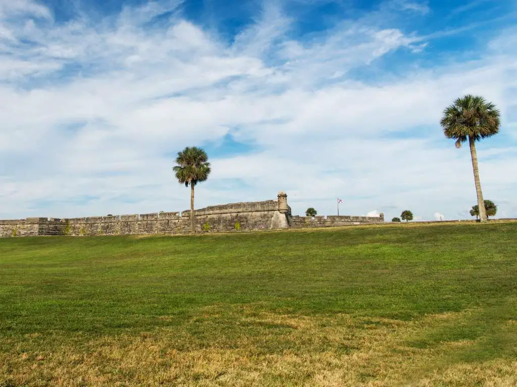 Stone walls of Castillo de San Marcos National Monument in Florida against backdrop of blue sky.