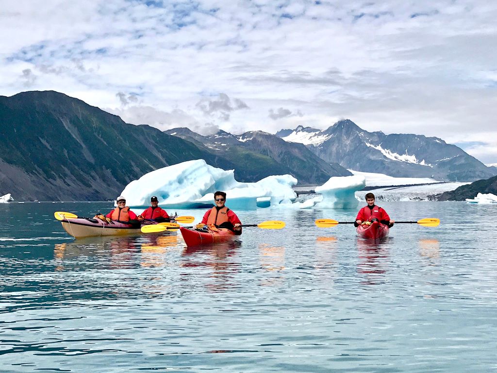 3 red kayaks floating among glaciers in Kenai fjords National Park