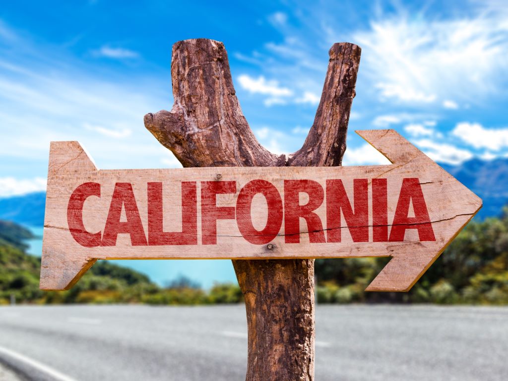 rustic wooden road sign pointing toward california