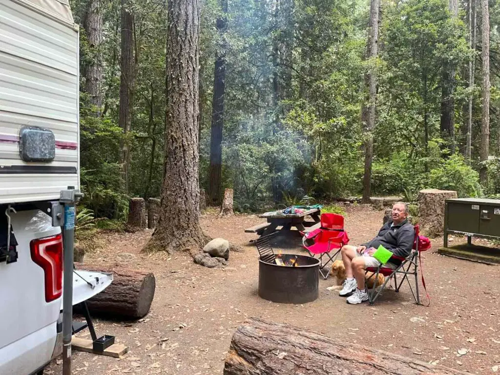 wooded campsite with man sitting in red chair