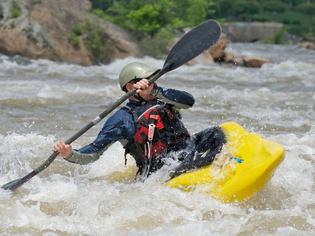 man in yellow kayak rafting through rapids