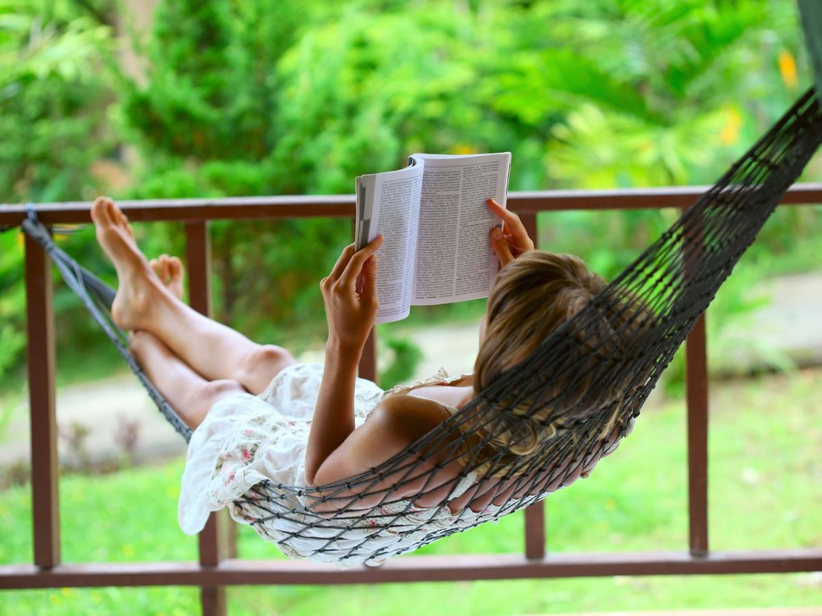 woman reading national park novel while swinging in hammock