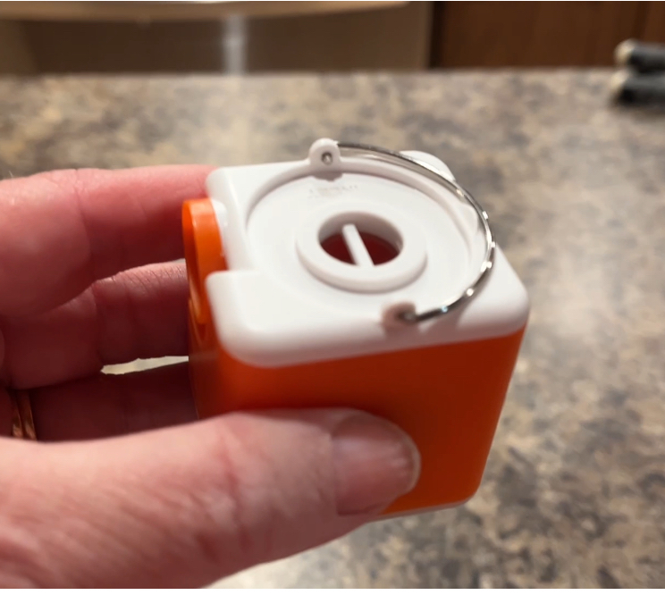 Hand holding an orange and white mini air pump