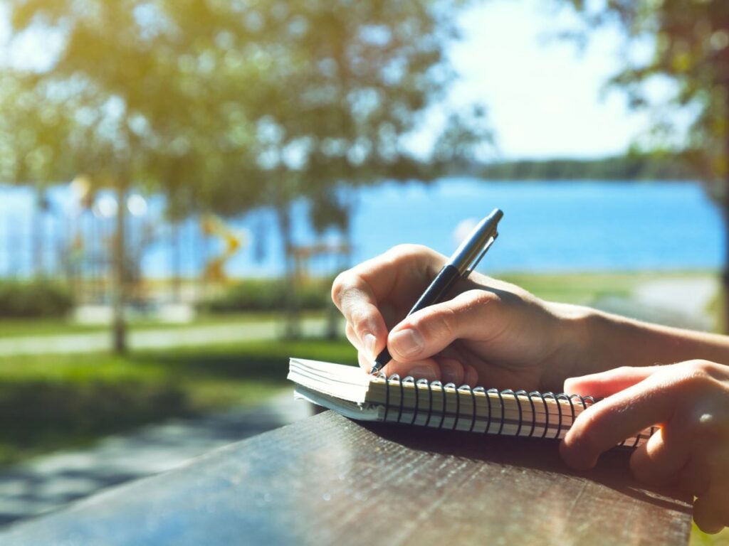 woman writing a vacation itinerary in a notebook