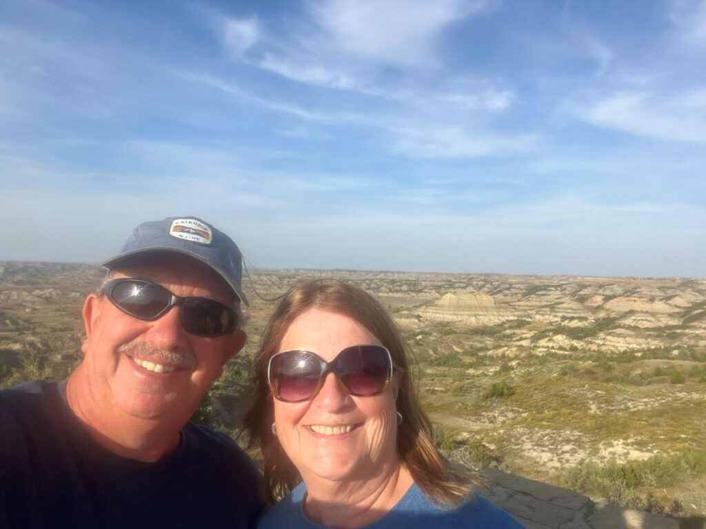 2 people in selfie pose in front of the badlands of Theodore Roosevelt National Park