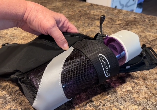 hand holding a belt that holds a waterbottle