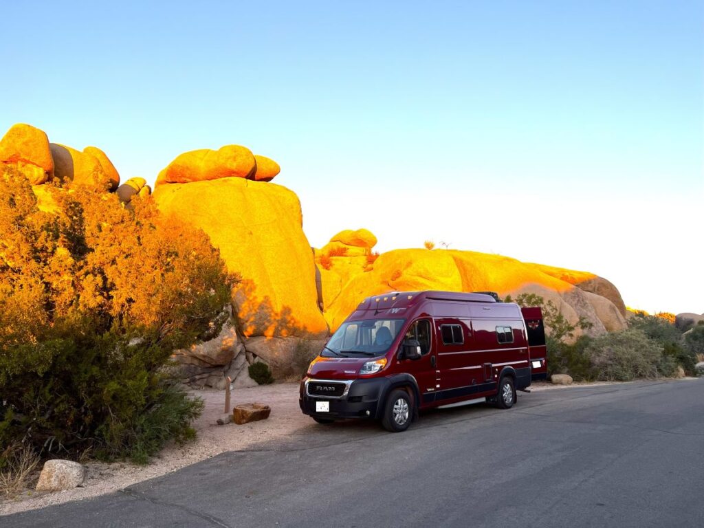 red campervan in front of huge boulders